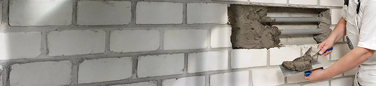 A man repairing a hole in the wall with mortar