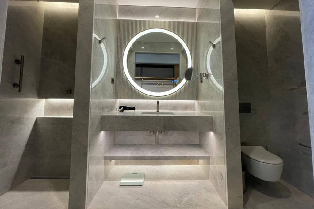 Hyatt Regency Izmir İstinyePark otelinin banyosunda yer alan mermer lavabo ve yuvarlak ayna.