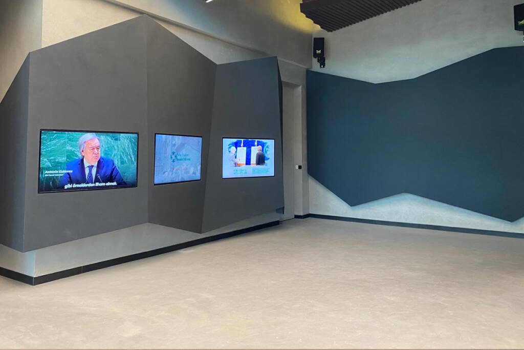 İklim Müzesi'nin sergi alanında, duvara entegre edilmiş ekranlar ve minimalist tasarım ögeleri.