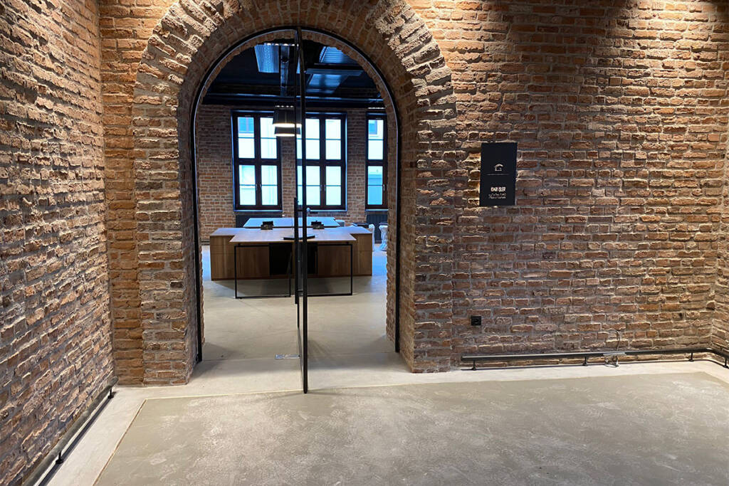 tuğla duvarlar arasında cam kapılı modern ofis girişi, zemin ARDEX ürünleri ile kaplanmış.