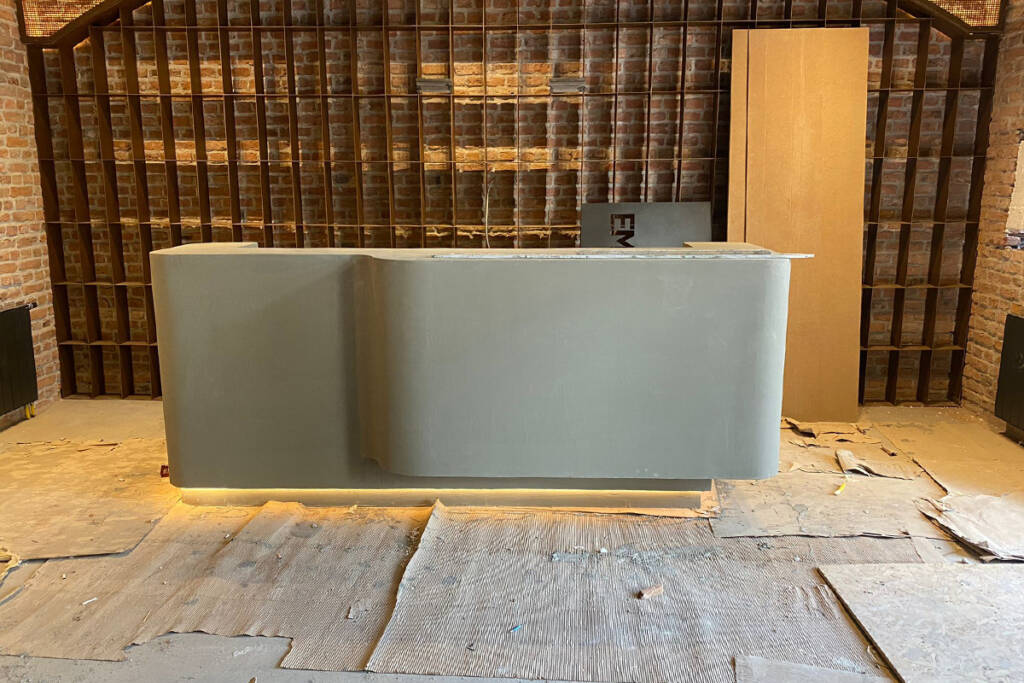 Modern bir resepsiyon alanında ARDEX K511 mikrobeton zemin kaplaması ve dekoratif tuğla duvarlar.