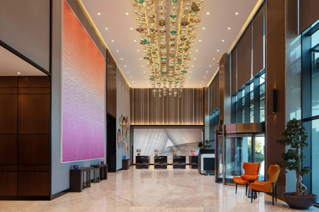 Sheraton İstanbul Esenyurt'un lobisi, modern tasarımı, renkli sanat eserleri ve etkileyici aydınlatmasıyla.