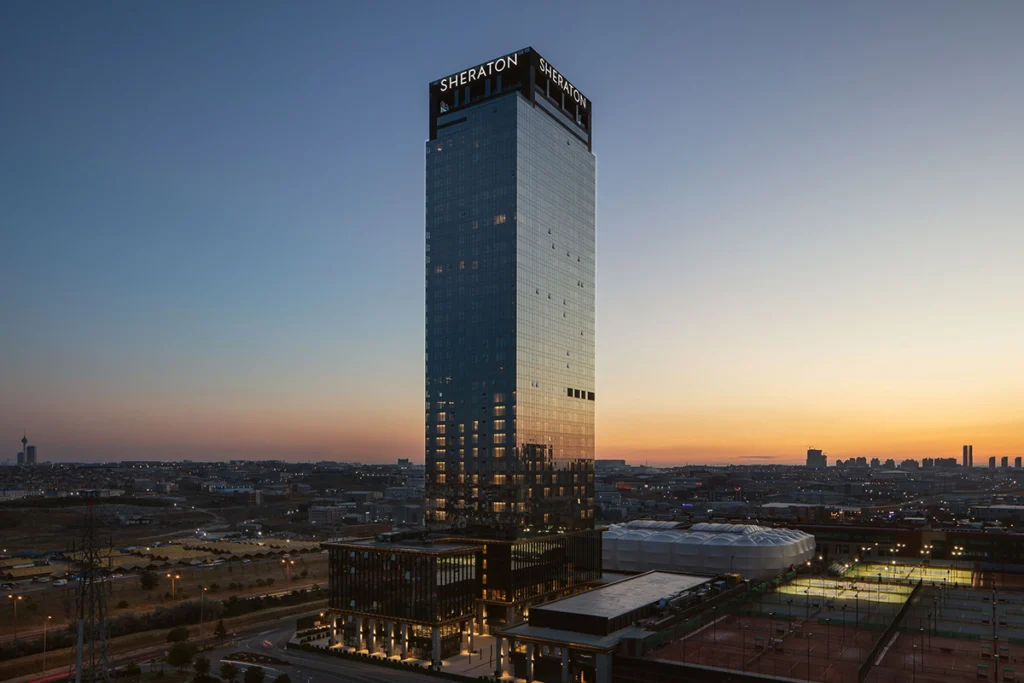 Akşam saatlerinde Sheraton İstanbul Esenyurt'un dış cephe görüntüsü, yüksek kule ve şehir manzarasıyla.
